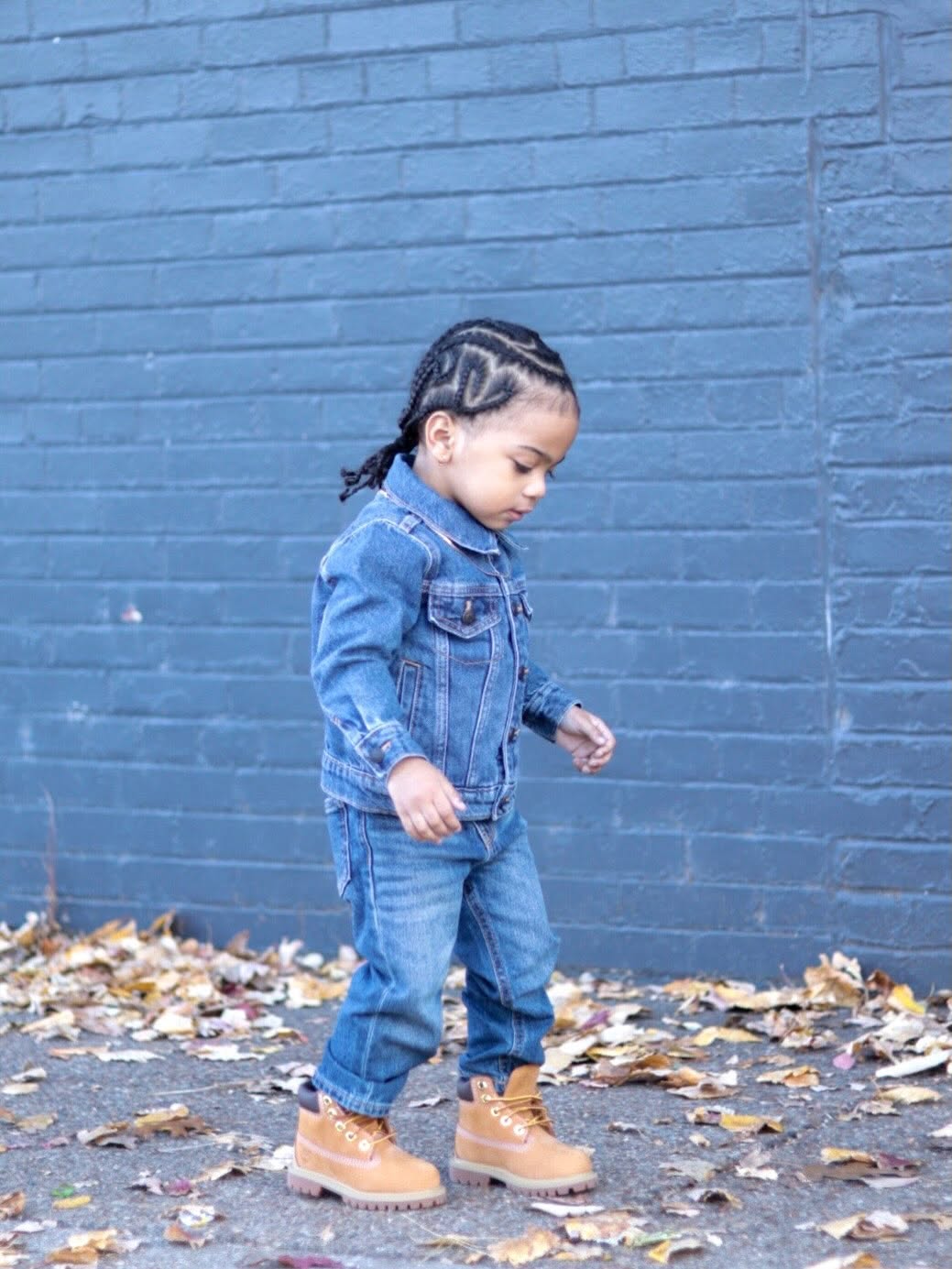 Twin boy walking in denim among fallen leaves