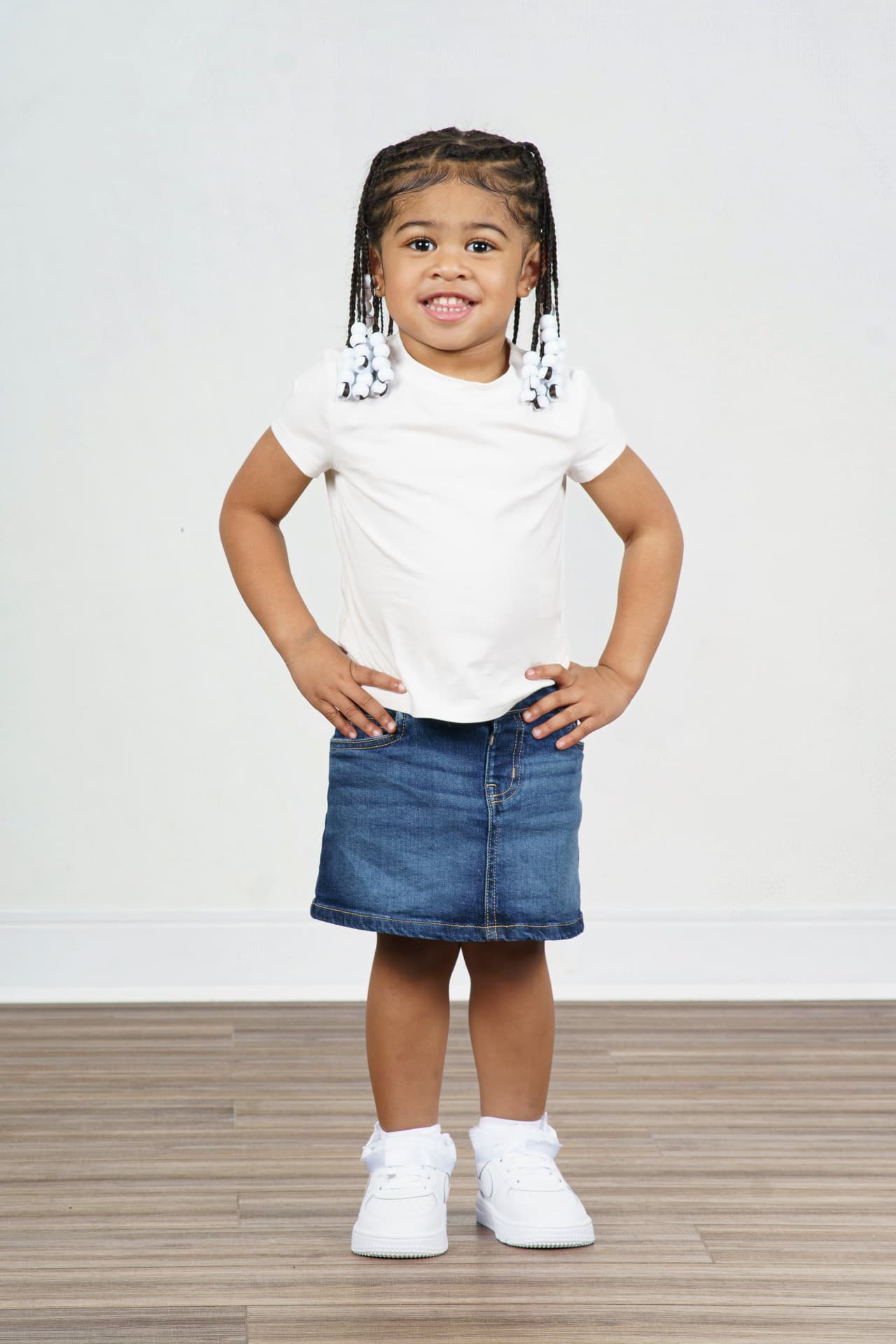 Twin girl standing with hands on hips in a white tee and denim skirt