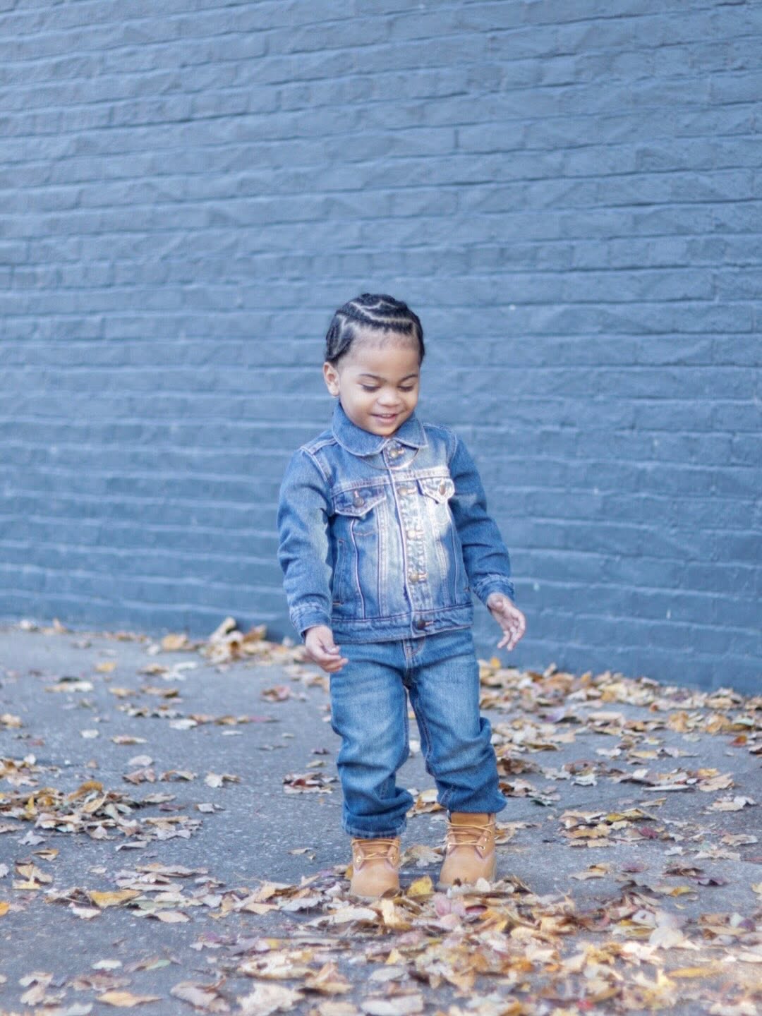 Twin boy looking down and smiling in a denim jacket