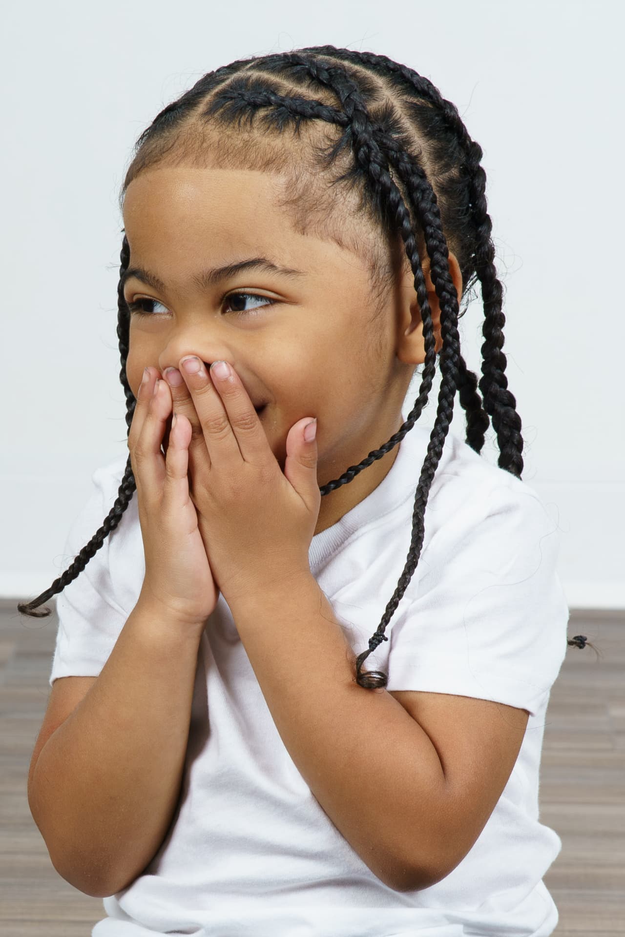 Twin girl in a white tee laughing with her hands over her mouth